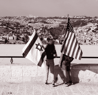 Two individuals standing with a US Flag and a flag of Israel