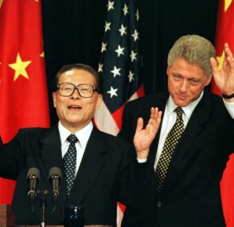 Chinese President Jiang Zemin and US President Bill Clinton wave during a joint press event in front of Chinese and American flags in 1997