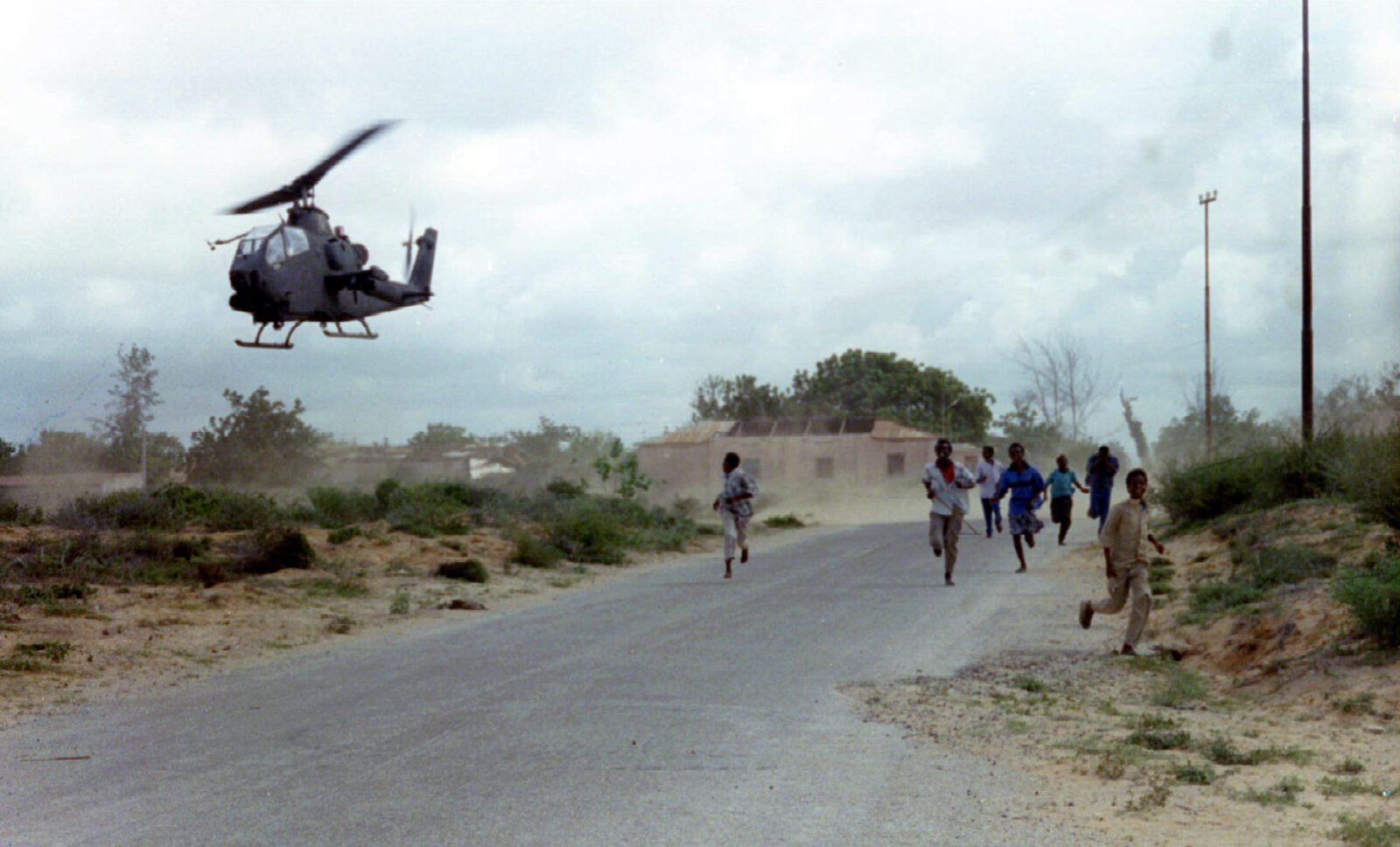 Children run as a US military helicopter hovers low over a road in Somalia