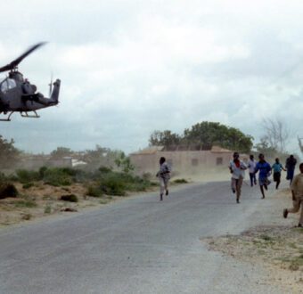 Children run as a US military helicopter hovers low over a road in Somalia