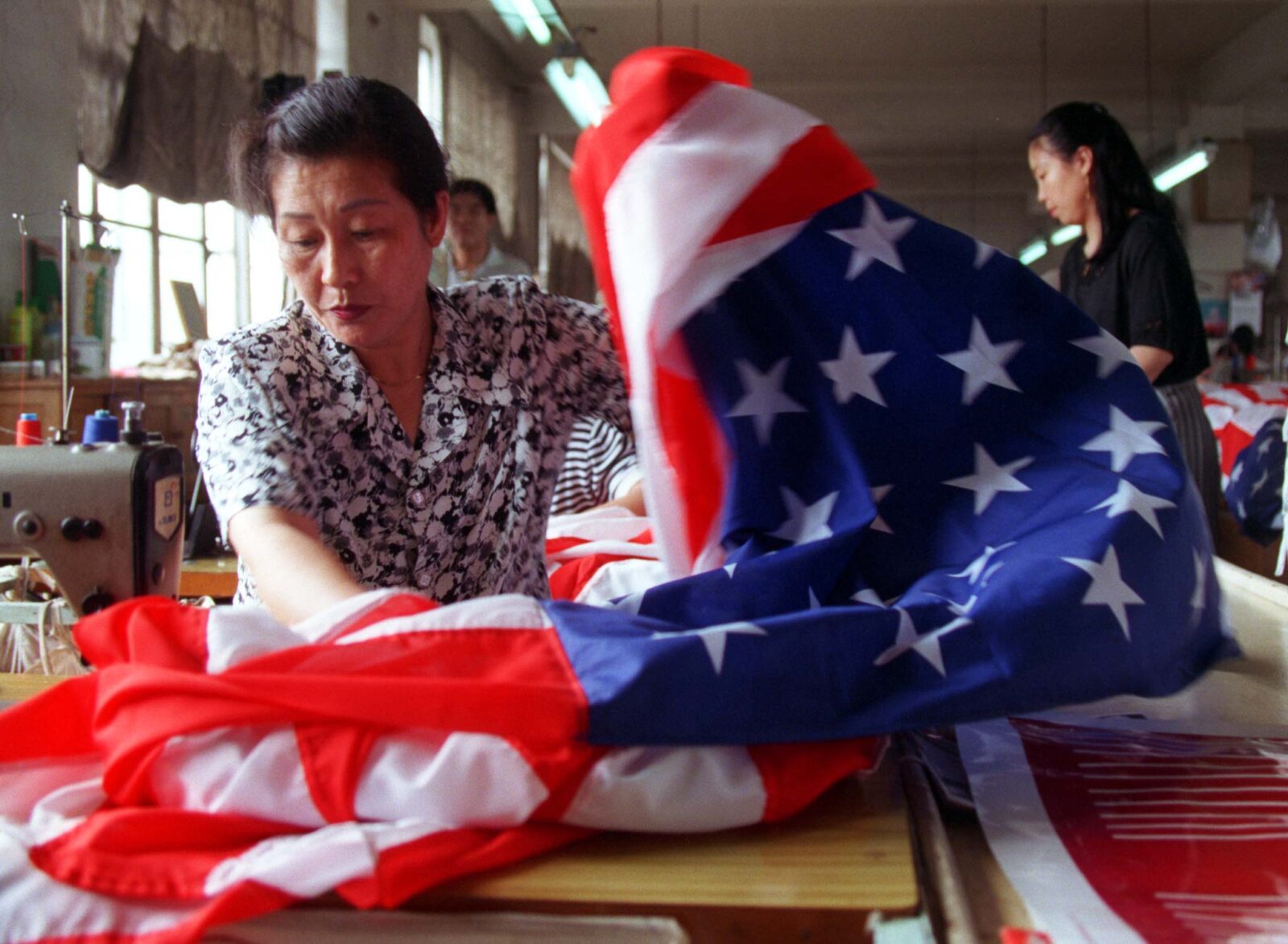 A seamstress at Chinese factors sews an American flag